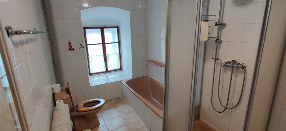 Koupelna v přízemí je vybavena toaletou, umyvadlem, vanou a sprchovým koutem