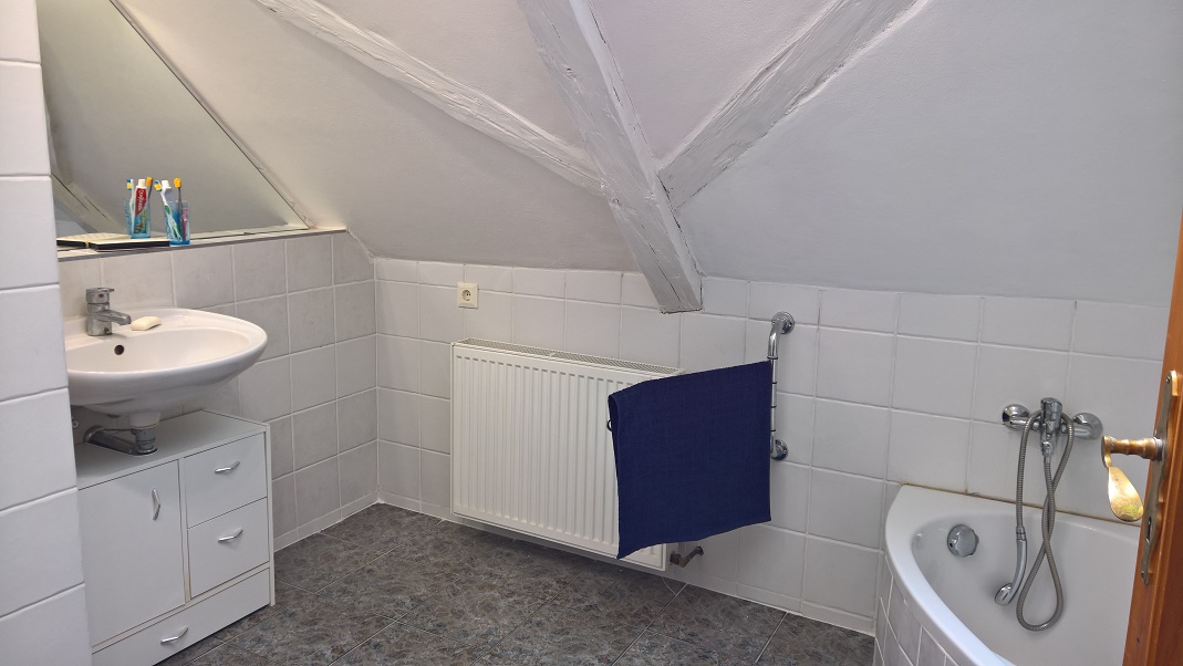 Koupelna v podkroví je vybavena umyvadlem, vanou, toaletou a pračkou