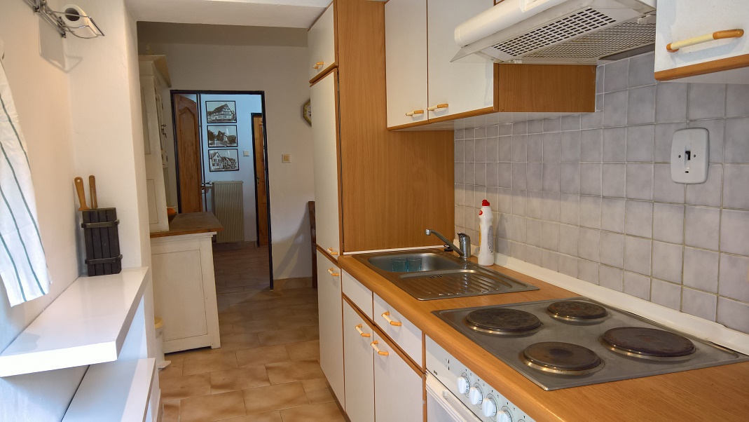 Kuchyně v přízemí je vybavena lednicí, elektrickým sporákem s troubou a rychlovarnou konvicí